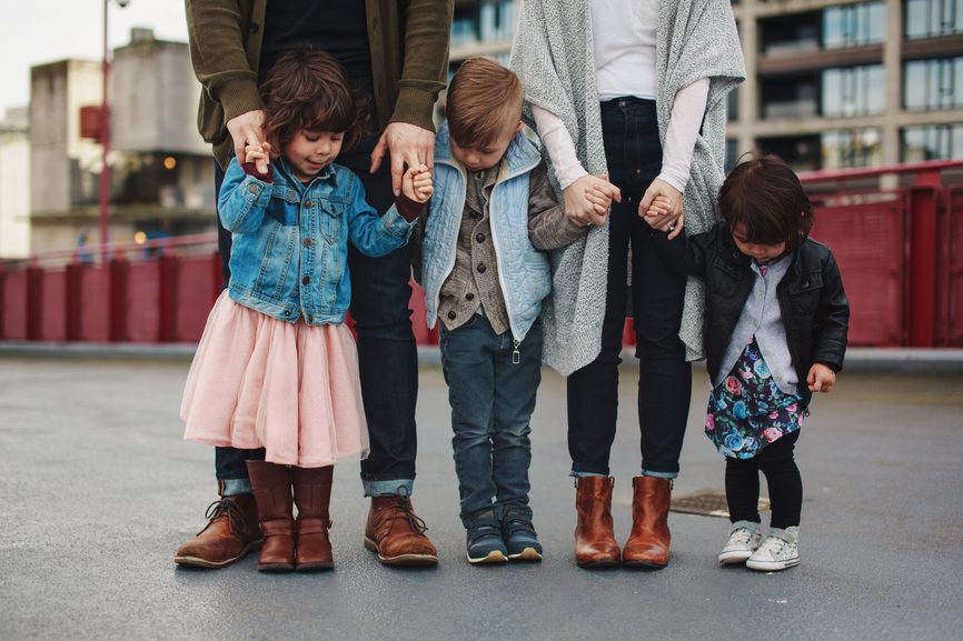 Family of 5 standing together looking down at their feet.