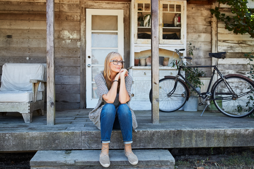 Woman sitting outside her wooden house.