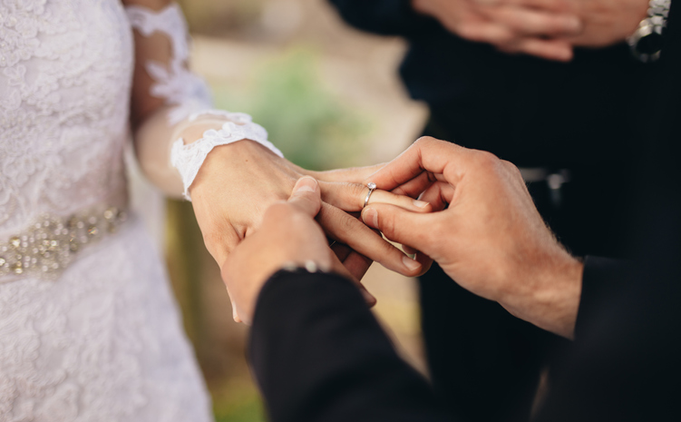 Man placing ring on woman's finger in marriage